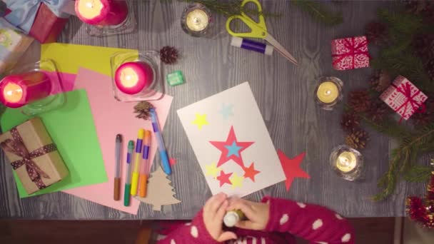 Artesanato infantil. Pequena menina cola cartão de Ano Novo — Vídeo de Stock