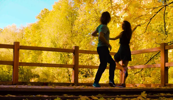 Silhouettes de jeunes couples heureux dansant sur le pont — Photo