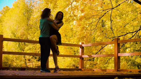 Silhouetten van jonge gelukkige paar dansen op de brug — Stockfoto