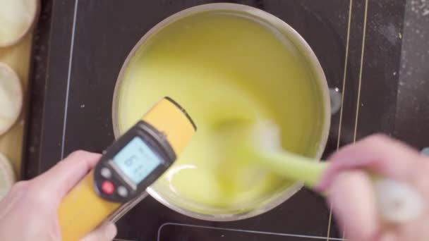 Mains d'un confiseur tenant un thermomètre infrarouge et mélangeant du caillé de citron — Video