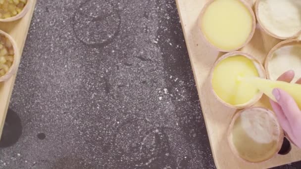 Hands of a confectioner pouring lemon curd into tartlets — Stock Video