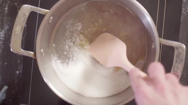 Hände eines Konditors, der Zucker am Boden der Pfanne schmelzen lässt — Stockvideo