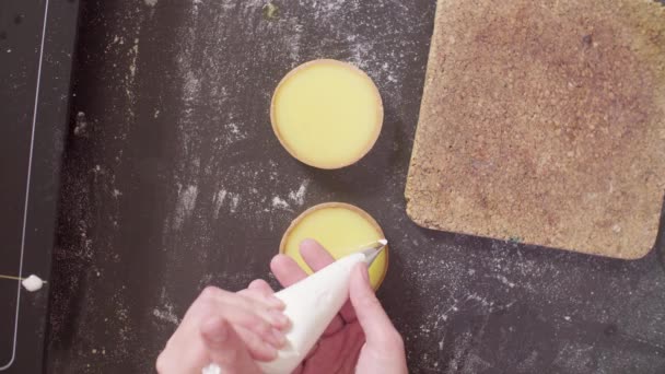 Handen van een banketbakker versieren tartlets met Zwitserse meringue — Stockvideo