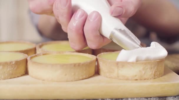 Mãos de um confeiteiro que decora tortinhas com merengue suíço — Vídeo de Stock