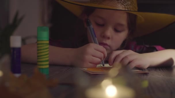 カードにクモの巣を描いている女の子。ハロウィーンのお祝いの準備 — ストック動画