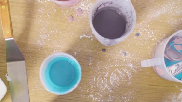 Чаши с разноцветной зеркальной глазурью на столе — стоковое видео