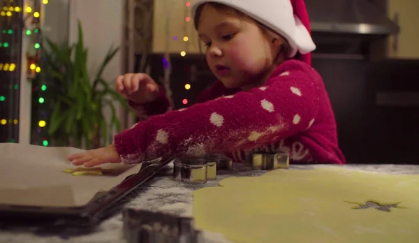 Malá holčička v červený svetr vyřezává vánoční cukroví — Stock fotografie