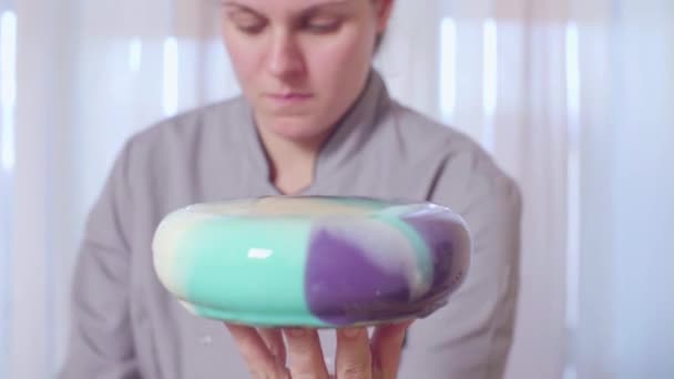 Руки кондитера кладут торт с зеркальной глазурью на держатель торта — стоковое видео