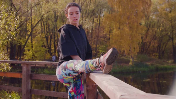 Frau macht Übungen auf der Brücke im Park — Stockfoto