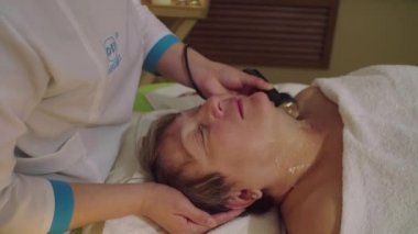 Genç Çinli doktor için üst düzey bir kadın kozmetik masaj yapıyor