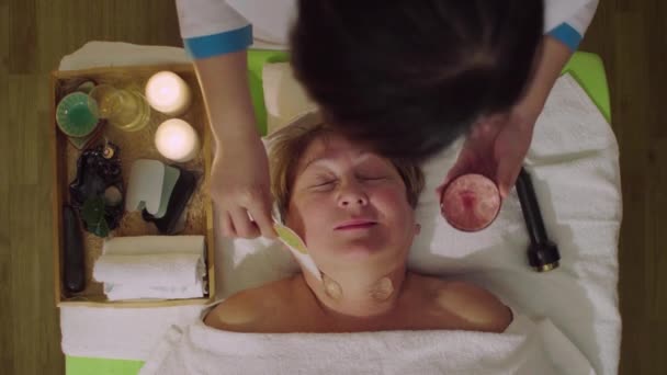 平面図です 年配の女性に首の美容マッサージをやっている若い中国人の医者 — ストック動画