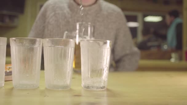 Jemand schüttet Wodka in gefrorene Gläser — Stockvideo