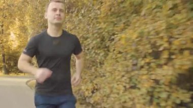 Enerjik adam parkta yol boyunca çalışan spor giyim