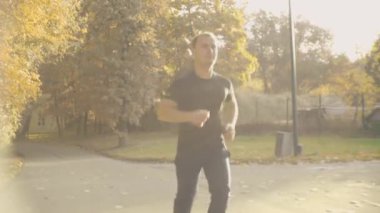 Enerjik adam parkta yol boyunca çalışan spor giyim