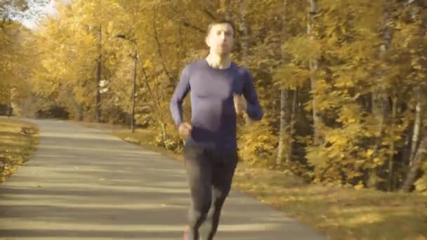 Fiatal férfi fut gyorsan végig az úton, a parkban — Stock videók