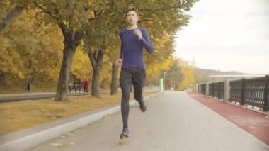 Parkta yol boyunca hızlı koşan genç adam