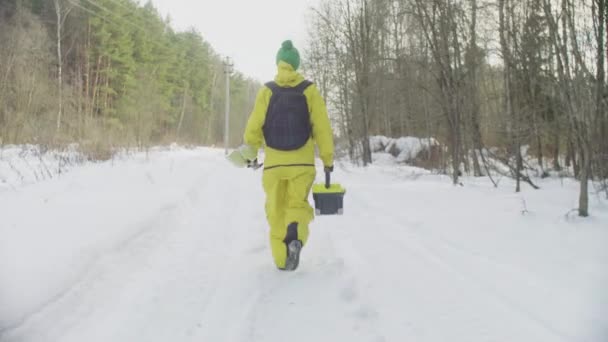 Ecoloog in sportkleding wandelen langs de weg in winter forest — Stockvideo