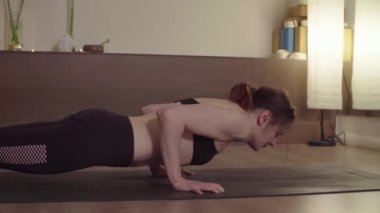 Chaturanga Dandasana 'da yoga egzersizleri yapan bir kadın.