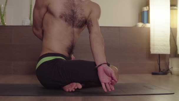 Silny przystojny mężczyzna praktykujący jogę-ardha Padmasana, twist — Wideo stockowe