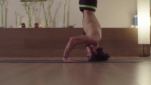 Ung man gör yoga asana - huvud stående balans — Stockvideo