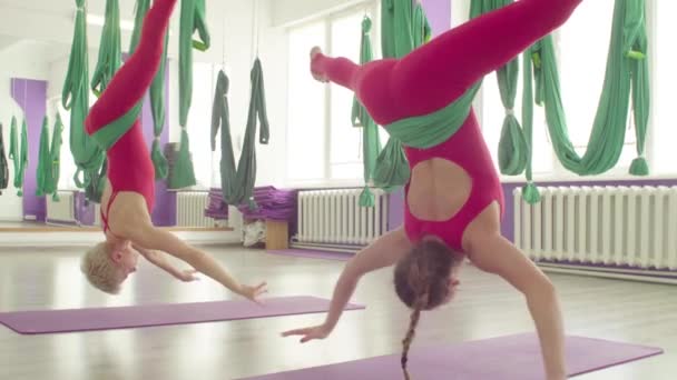 Yoga antigravedad. Dos mujeres atractivas haciendo ejercicios en hamacas — Vídeo de stock