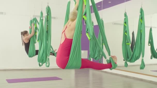 Schwerkraft-Yoga. zwei Frauen machen Übungen in Hängematten — Stockvideo