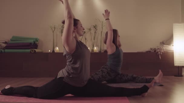 Дві веселі жінки займаються вправами йоги шпагат — стокове відео