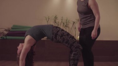 Yoga yapan kadınlar, arkadaşı ona yardım ediyor.