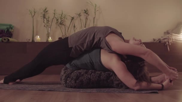 Partner yoga. Twee vrouwen doen Paschimottanasana in paar — Stockvideo