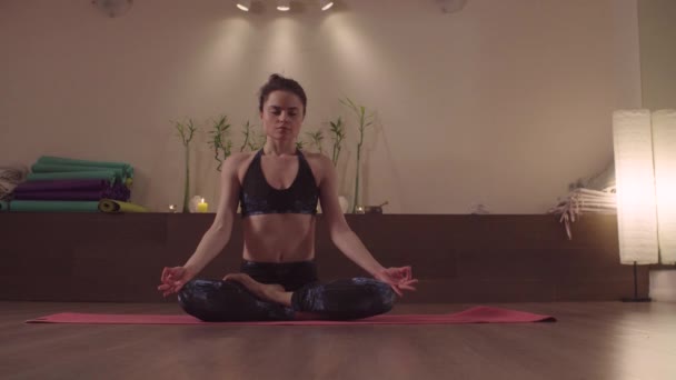 Young woman sitting in lotus pose in studio — 비디오