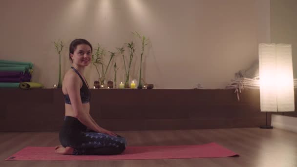 Leende kvinna sitter i yogastudio — Stockvideo