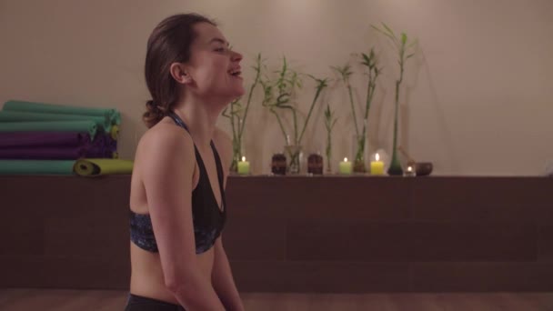 Femme souriante assise dans un studio de yoga — Video