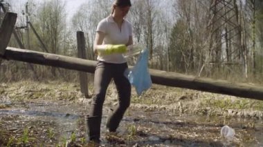 Woman volunteer collecting garbage in the pond