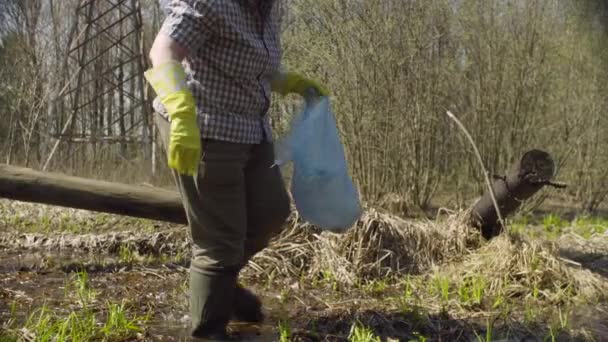 森林池でゴミを集める古い緑の活動家 — ストック動画