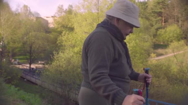 Senior vrouw Nordic wandelen langs de heuvel — Stockvideo