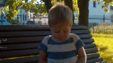 Küçük çocuk bir bankta oturan ve topuz yemek