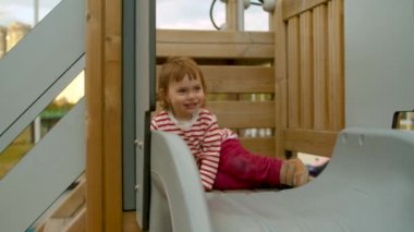 Küçük kız bir slaytın üstünde oturuyor