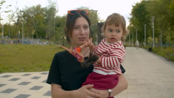 Anya sétál a parkban kislány a karjaiban — Stock videók