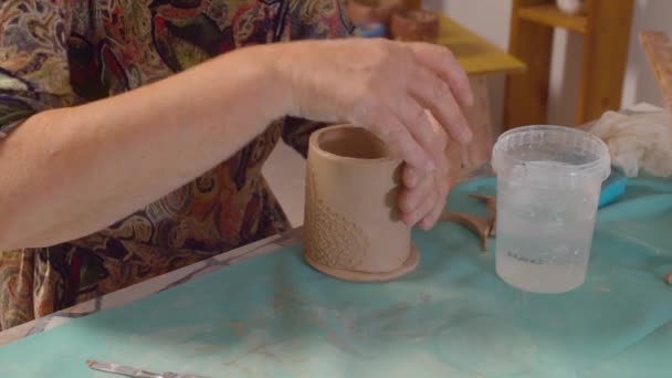 Senior potter attaches the bottom to the mug — Stock Video