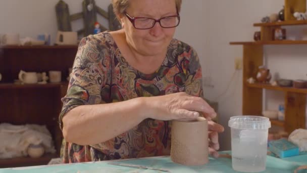 La donna anziana allinea il bordo della tazza di argilla — Video Stock