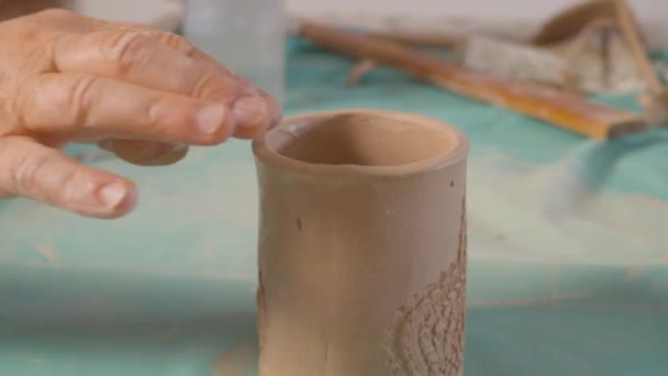 Старшие женские руки выравнивает край глиняной кружки — стоковое видео