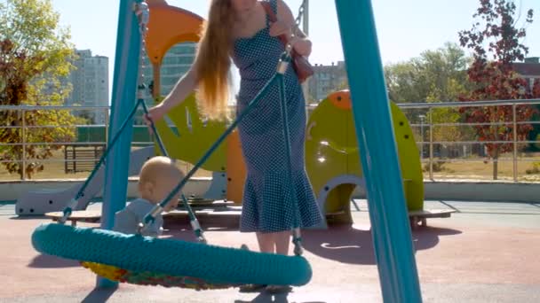 Ung mamma driver Baby Boy på en swing — Stockvideo