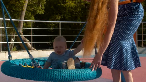 Mãe ajudando bebê menino sair do balanço — Vídeo de Stock