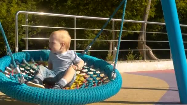 Ongelukkige kleine jongen zwaaien op een schommel — Stockvideo