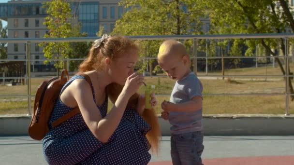 Mamá mostrando a su hijo cómo soplar burbujas de jabón — Vídeos de Stock