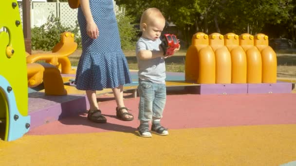 Niño con el juguete en el patio de recreo — Vídeos de Stock