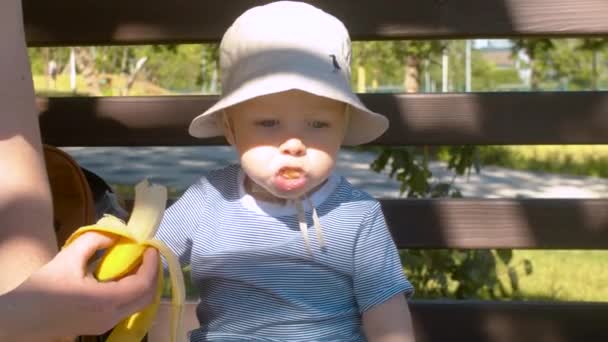 Bebé comiendo plátano en el parque — Vídeos de Stock