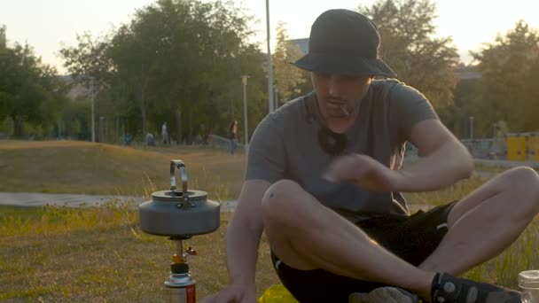 Kettle on a camp stove. A man adjusts gas — Stock Video