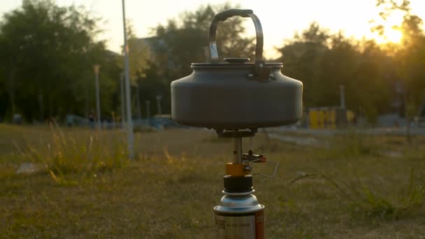 Kettle heating on a camp stove in a park — Stock Video