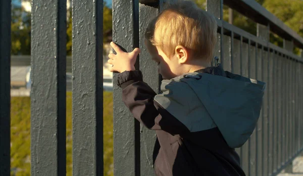 Klein kind staat in de buurt van het hek — Stockfoto